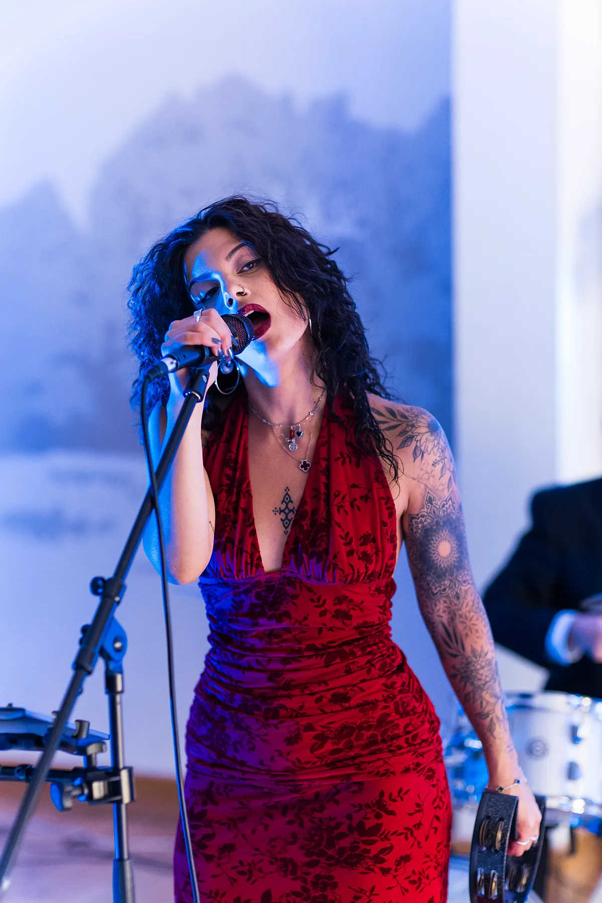 A singer performing into a microphone under blue stage lighting